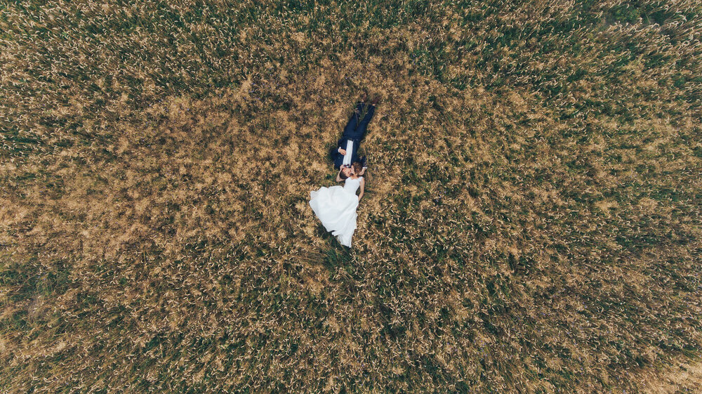aerial photograph of bride and groom laying in field.jpg